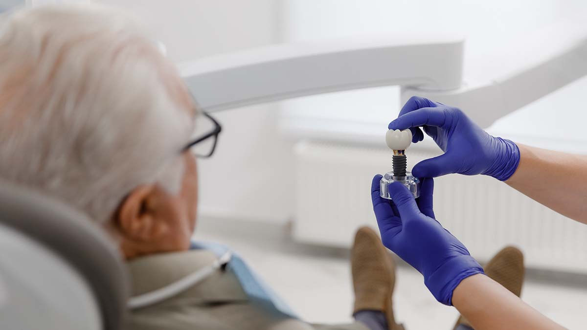Dentist showing dental implant model to senior patient in Richmond clinic